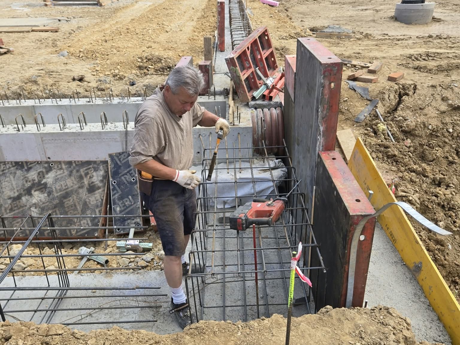 Robotník viaže výstuž medzi debnením kanála