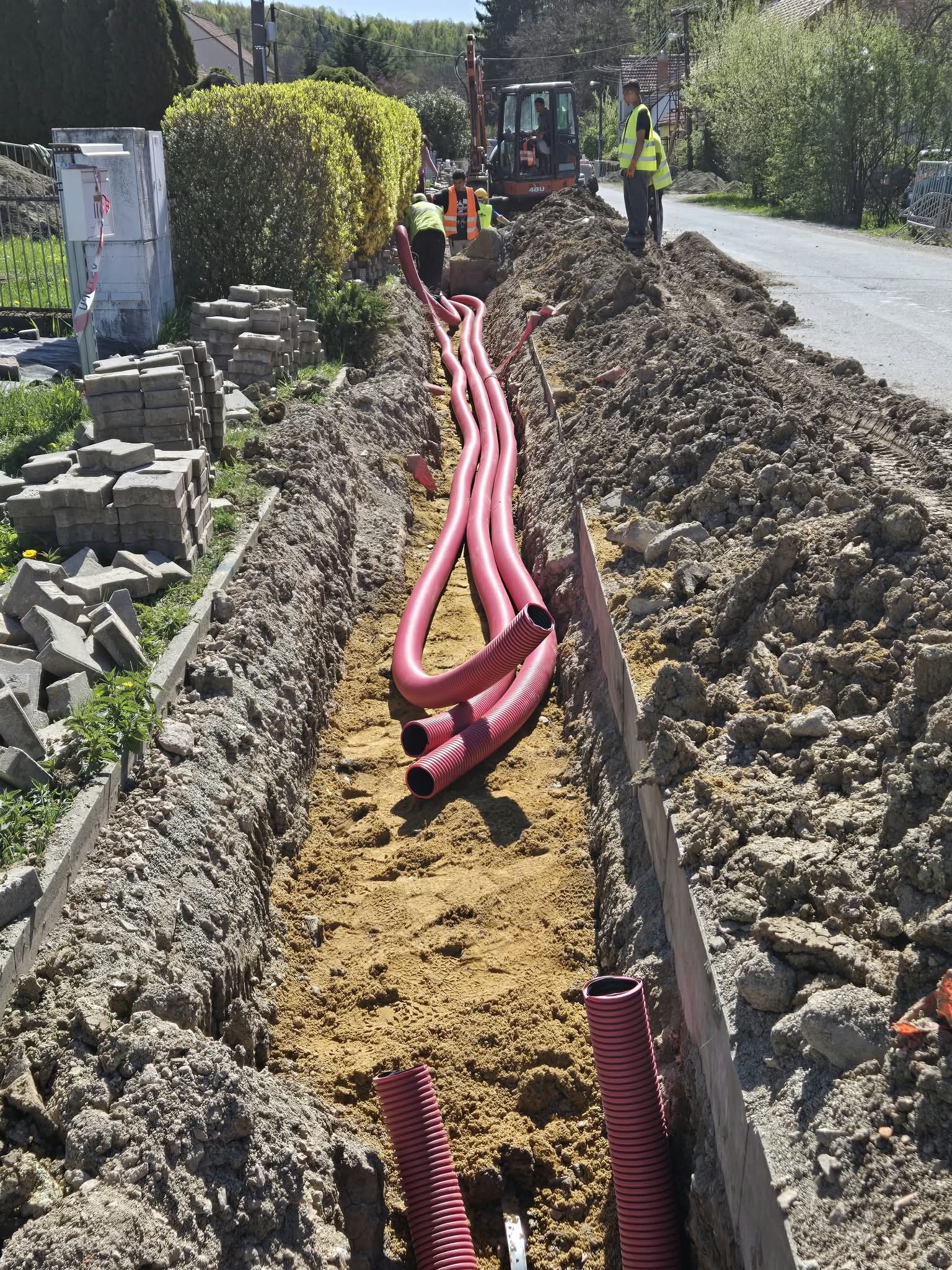 Červené chráničky uložené v otvorenej ryhe popri ceste