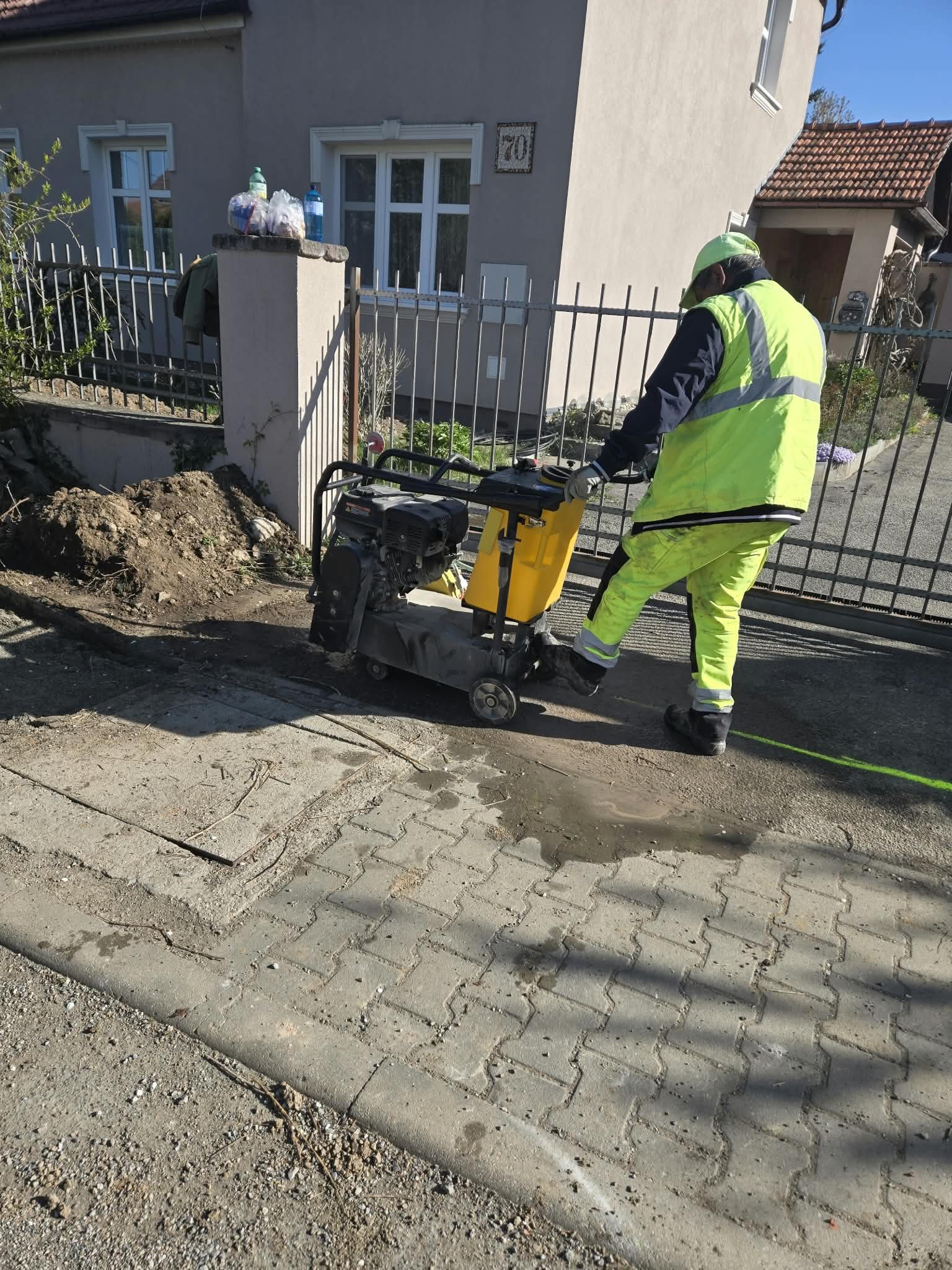 Robotník hutní podklad chodníka vibračnou doskou pred bránou