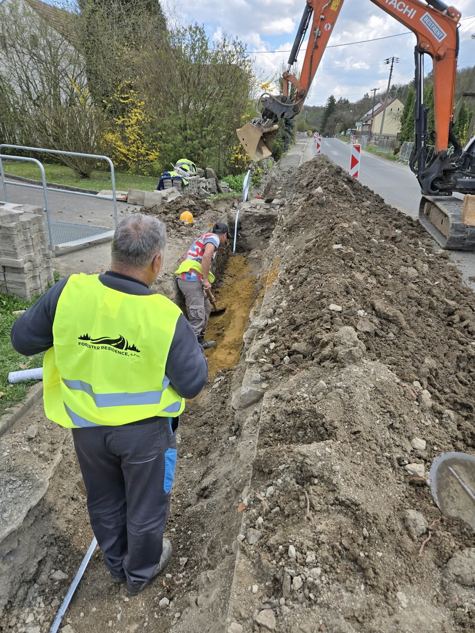 Rýpadlo a robotníci pri výkope pre káble NN popri ceste