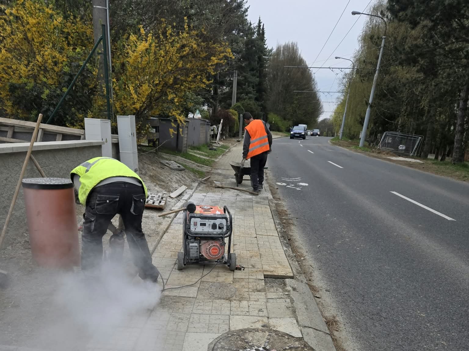 Robotník reže dlažbu chodníka popri ceste
